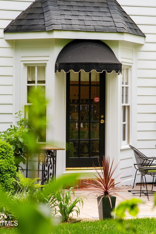 view of exterior entry with a shingled roof