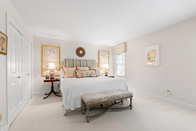 bedroom featuring a closet, baseboards, and light carpet