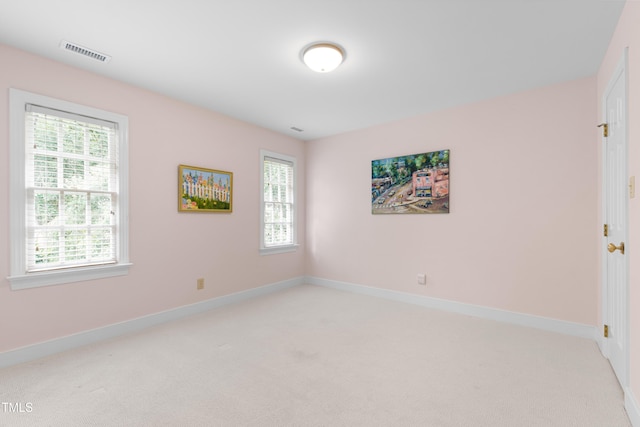 empty room featuring light carpet, healthy amount of natural light, and baseboards
