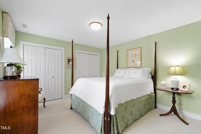 bedroom featuring two closets, light carpet, and baseboards