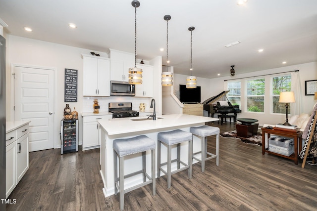 kitchen with dark wood finished floors, wine cooler, a sink, decorative backsplash, and appliances with stainless steel finishes