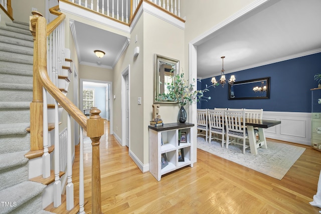 foyer entrance with stairway, an inviting chandelier, ornamental molding, and wood finished floors