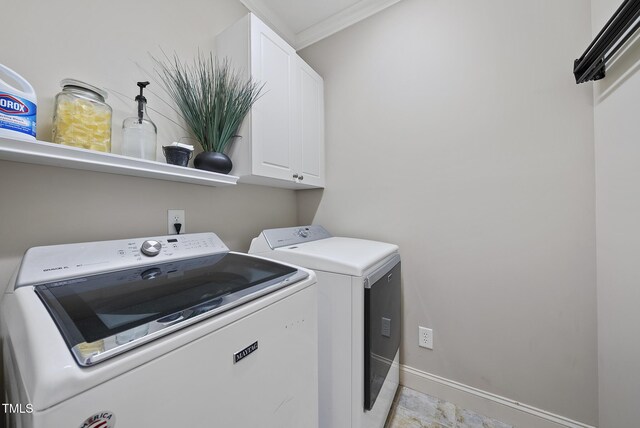 clothes washing area featuring cabinet space, baseboards, crown molding, and washer and dryer