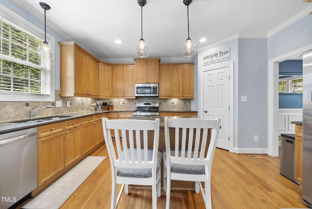 kitchen featuring a sink, light wood-style floors, stainless steel appliances, backsplash, and ornamental molding
