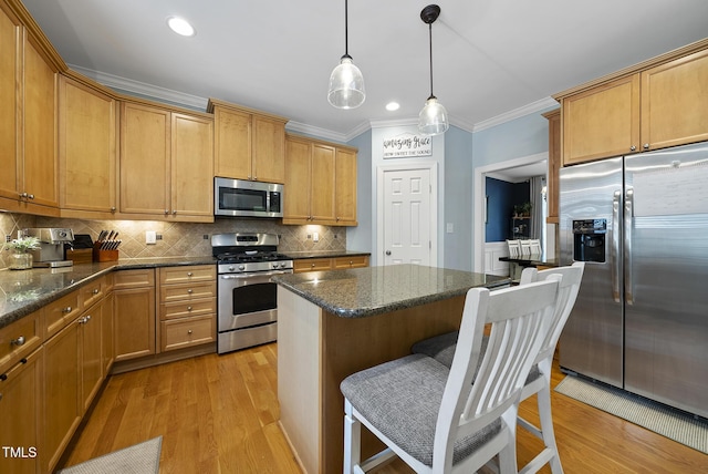 kitchen featuring light wood finished floors, stainless steel appliances, tasteful backsplash, ornamental molding, and a breakfast bar area