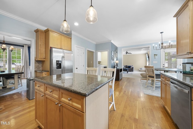 kitchen featuring plenty of natural light, appliances with stainless steel finishes, light wood-style flooring, and a notable chandelier