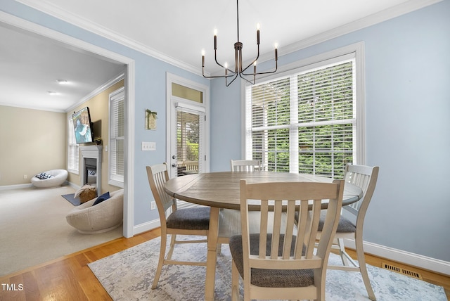 dining room with wood finished floors, baseboards, a fireplace, and a notable chandelier