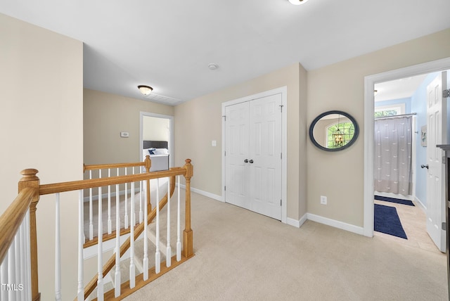 hall with light colored carpet, baseboards, an upstairs landing, and visible vents
