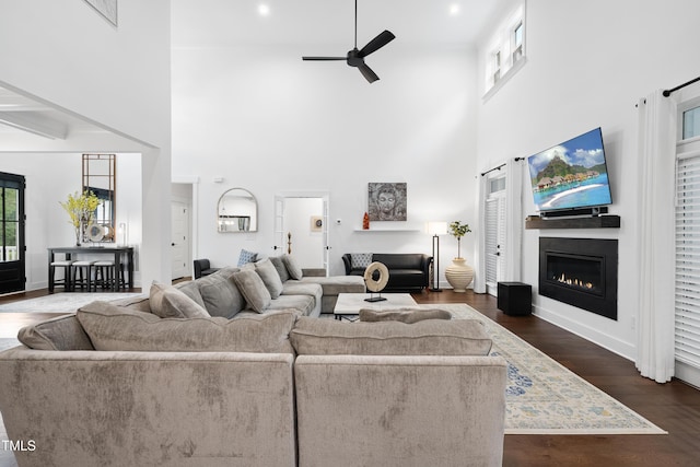 6024 Lunenburg Dr, Raleigh, NC 27603 - living room with wood finished floors, a glass covered fireplace, ceiling fan, a towering ceiling, and baseboards