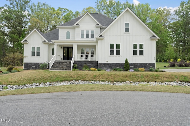 6024 Lunenburg Dr, Raleigh, NC 27603 - view of front of home with stairway, a shingled roof, board and batten siding, covered porch, and a front yard