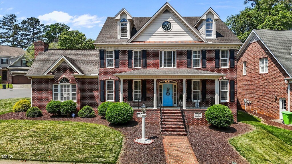 5619 Bennettwood Ct, Raleigh, NC 27612 - colonial inspired home with brick siding, a shingled roof, a front lawn, and covered porch