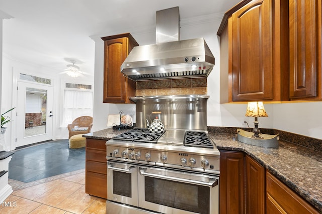 6212 Trevor Ct, Raleigh, NC 27613 - kitchen with wall chimney range hood, a ceiling fan, crown molding, dark stone counters, and range with two ovens