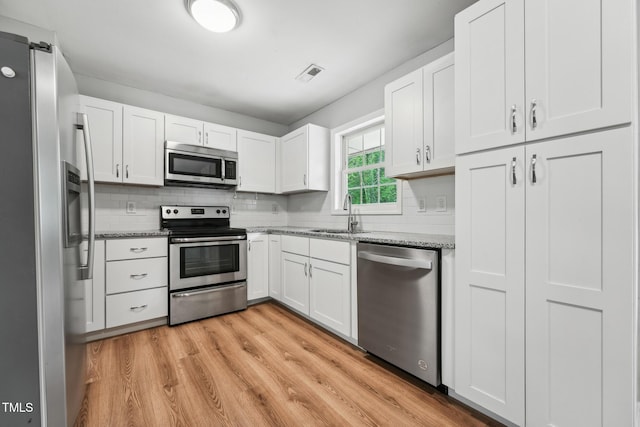 508 Solar Dr, Raleigh, NC 27610 - kitchen featuring stainless steel appliances, light wood-style flooring, a sink, tasteful backsplash, and visible vents