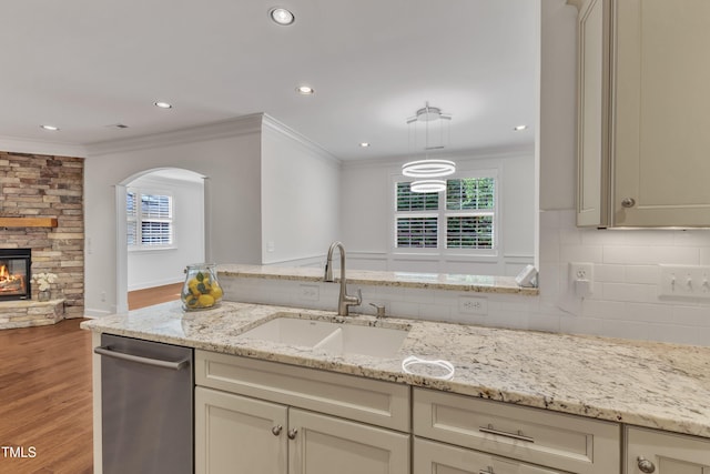 644 Angelica Cir, Cary, NC 27518 - kitchen featuring a sink, stainless steel dishwasher, ornamental molding, arched walkways, and light wood-type flooring