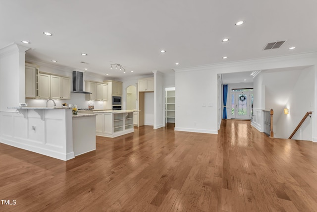 644 Angelica Cir, Cary, NC 27518 - kitchen featuring wall chimney exhaust hood, ornamental molding, a peninsula, a kitchen breakfast bar, and recessed lighting