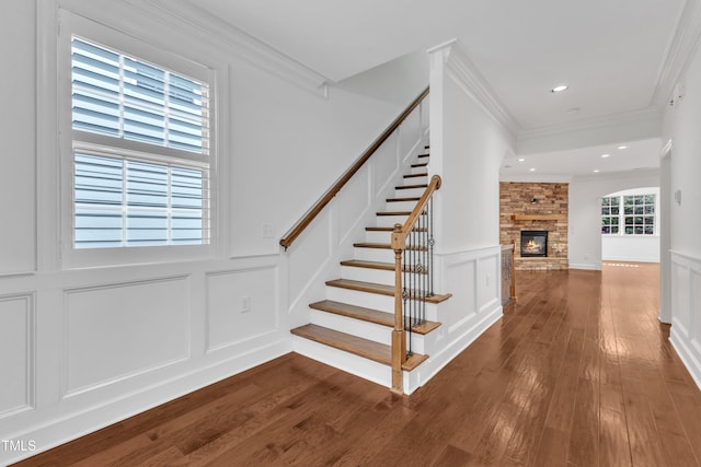 644 Angelica Cir, Cary, NC 27518 - stairs with a decorative wall, ornamental molding, wood finished floors, a wainscoted wall, and a stone fireplace