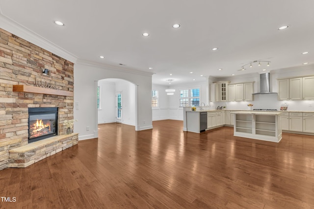 644 Angelica Cir, Cary, NC 27518 - unfurnished living room featuring ornamental molding, arched walkways, a fireplace, wood finished floors, and a sink