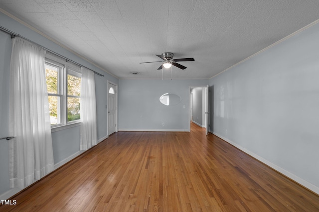 spare room featuring ornamental molding, baseboards, a ceiling fan, and wood finished floors