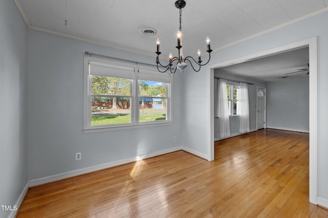 unfurnished dining area featuring crown molding, wood finished floors, baseboards, a notable chandelier, and visible vents