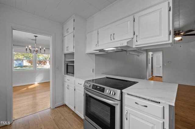 kitchen with stainless steel range with electric cooktop, under cabinet range hood, light stone countertops, and white cabinetry
