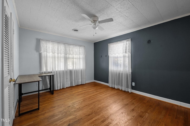 unfurnished bedroom featuring crown molding, wood finished floors, multiple windows, and visible vents