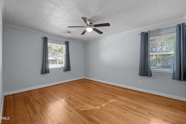spare room featuring ceiling fan, baseboards, crown molding, and light wood finished floors