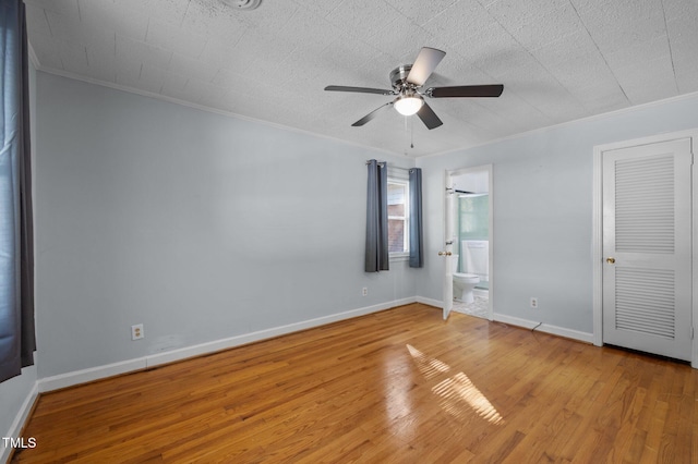 unfurnished bedroom with ensuite bath, light wood finished floors, baseboards, and ornamental molding