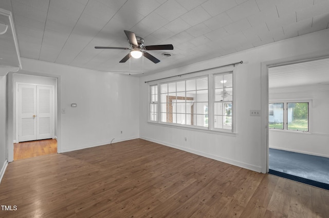 unfurnished living room with baseboards, a ceiling fan, wood finished floors, and visible vents