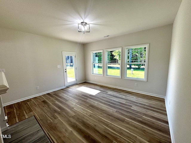 interior space with dark wood-type flooring, visible vents, and baseboards