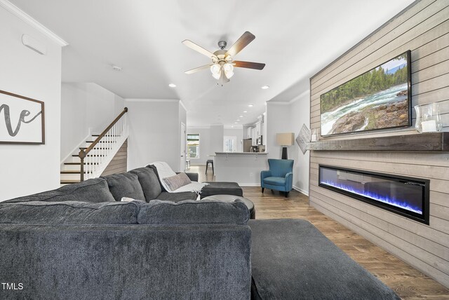 6511 Academic Ave, Raleigh, NC 27616 - living area featuring stairway, crown molding, a ceiling fan, wood finished floors, and a glass covered fireplace