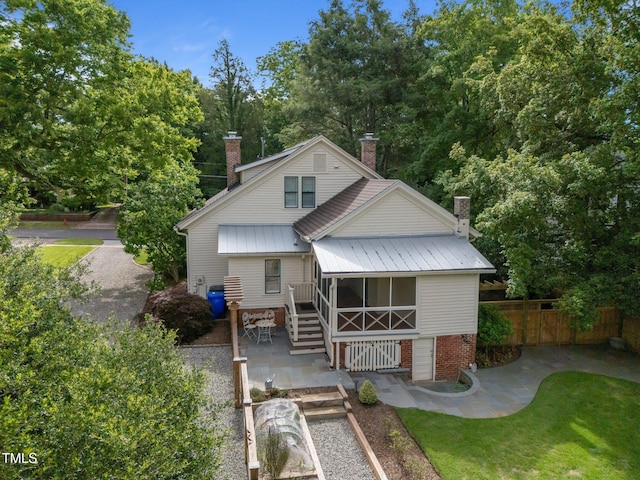 109 N Hassel St, Hillsborough, NC 27278 - back of house featuring a chimney, a sunroom, a patio area, and a metal roof