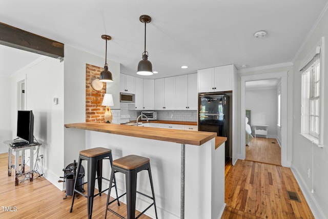 109 N Hassel St, Hillsborough, NC 27278 - kitchen with wood counters, stainless steel microwave, light wood-type flooring, freestanding refrigerator, and crown molding