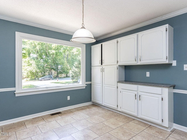 unfurnished dining area featuring crown molding, baseboards, a textured ceiling, and visible vents