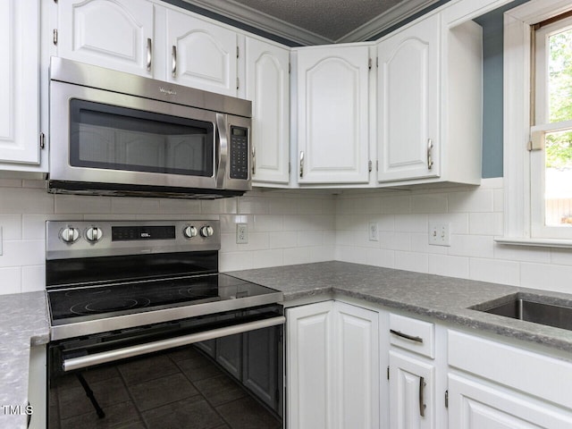 kitchen featuring appliances with stainless steel finishes, white cabinets, decorative backsplash, and tile patterned floors