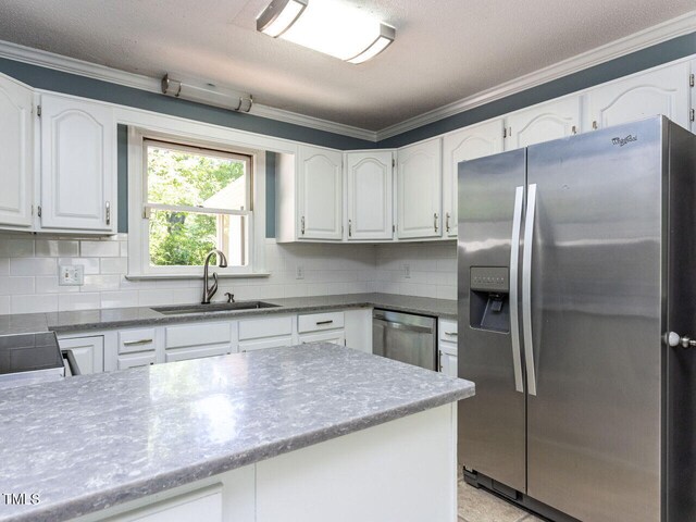 kitchen with white cabinets, a sink, stainless steel appliances, tasteful backsplash, and ornamental molding