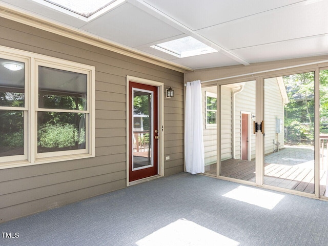 unfurnished sunroom with carpet floors, wooden walls, and a skylight