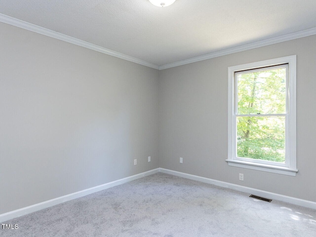carpeted spare room featuring visible vents, ornamental molding, baseboards, and plenty of natural light