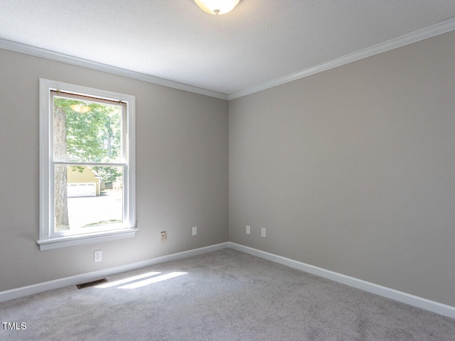 carpeted spare room featuring crown molding, baseboards, and visible vents