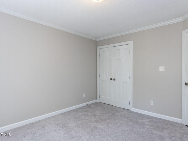 unfurnished bedroom with crown molding, carpet flooring, baseboards, and a closet