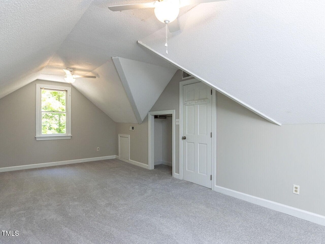 bonus room with carpet floors, ceiling fan, vaulted ceiling, and a textured ceiling