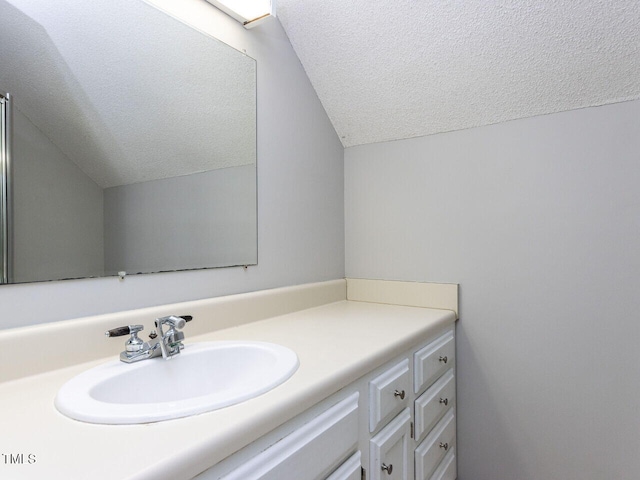 bathroom featuring a textured ceiling, lofted ceiling, and vanity