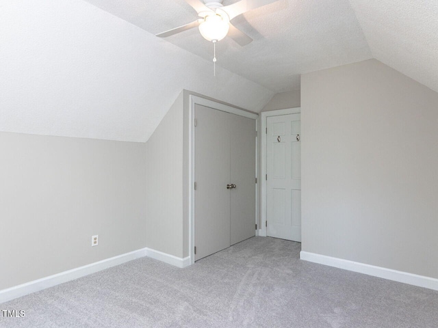bonus room with light colored carpet, baseboards, a textured ceiling, and lofted ceiling