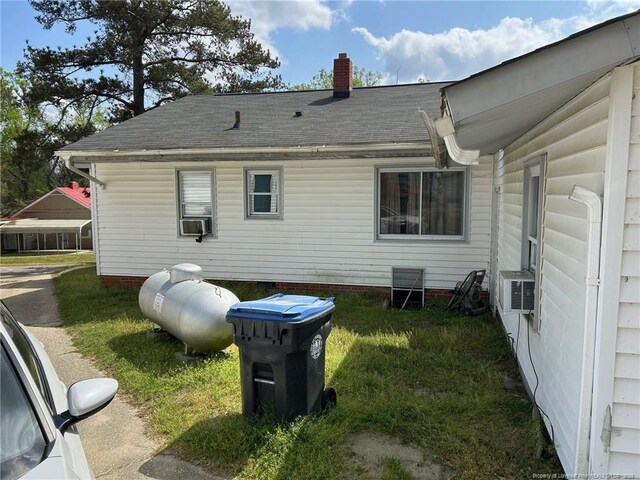 back of property featuring cooling unit, roof with shingles, and a chimney