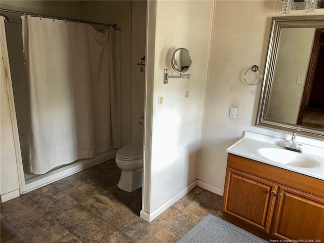 full bath featuring vanity, stone finish flooring, toilet, shower / tub combo, and baseboards