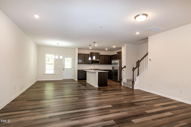 kitchen featuring light countertops, dark brown cabinets, appliances with stainless steel finishes, open floor plan, and a notable chandelier