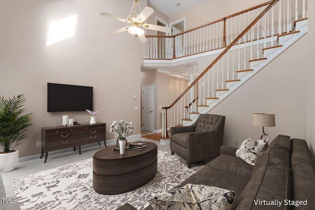 living room with baseboards, a high ceiling, stairs, ceiling fan, and carpet floors