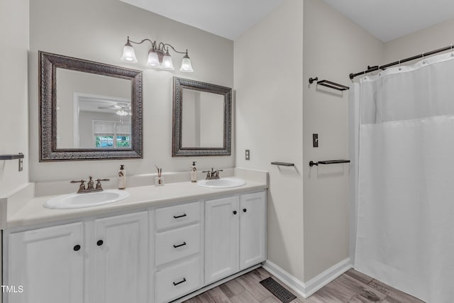 1311 Theodore Ln, Durham, NC 27703 - full bath featuring double vanity, wood finished floors, baseboards, and a shower with shower curtain
