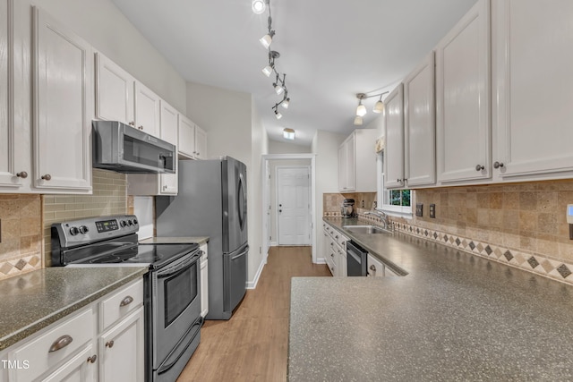 1311 Theodore Ln, Durham, NC 27703 - kitchen featuring appliances with stainless steel finishes, dark countertops, white cabinetry, light wood finished floors, and decorative backsplash