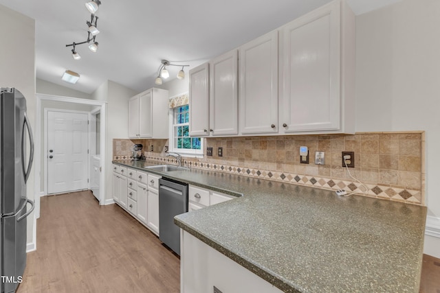 1311 Theodore Ln, Durham, NC 27703 - kitchen featuring stainless steel appliances, a sink, dark countertops, light wood-style flooring, and vaulted ceiling