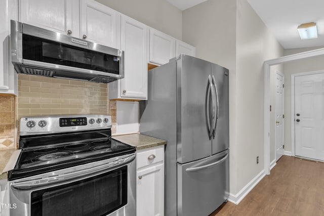 1311 Theodore Ln, Durham, NC 27703 - kitchen with appliances with stainless steel finishes, white cabinets, wood finished floors, and backsplash